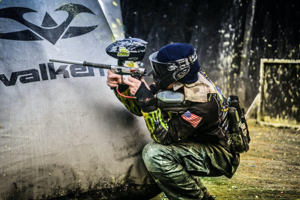 Player crouching behind an air bladder playing paintball